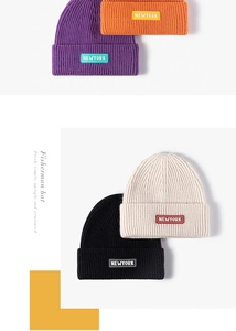 Detail of ribbed knit beanies with NEWYORK patch in purple, orange, black and beige colors