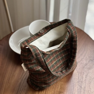Detail of plaid wool fabric small tote bag showing magnetic clasp and simple wish label