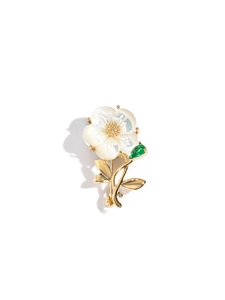 Close-up of elegant flower brooch with shell petals and green teardrop gemstone