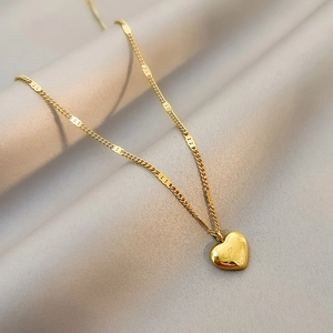 Elegant gold titanium heart necklace with Love engraving on silky gray fabric
