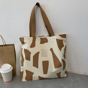 Detail of canvas tote with geometric print and Good Student patch in a lifestyle setting