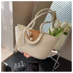 Detail of beige straw tote bag with brown leather flap and pearl buckle detail