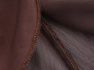 Detail of deep brown pleated chiffon fabric featuring tight overlock stitching on the edge
