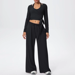 Détail d'un ensemble de yoga noir avec haut cache-cœur à manches longues et pantalon large
