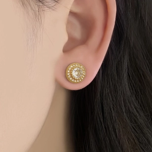 Close-up of elegant gold zircon flower stud earrings worn on a female model's ear