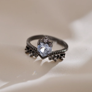 Macro shot of a gold-plated crown ring featuring a central heart crystal on beige fabric