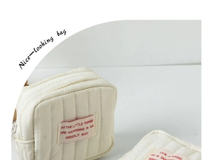 Detailaufnahme einer kleinen gesteppten cremefarbenen Tasche mit einem Stoffetikett