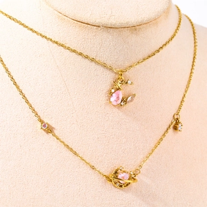 Detailed close-up of golden necklaces with pink heart Saturn and moon pearl pendants
