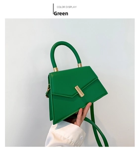 Detail of green PU leather handbag with gold metal clasp and curved top handle