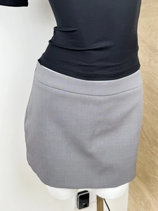 Detailed view of grey mini skirt fabric texture and fine stitching on a mannequin