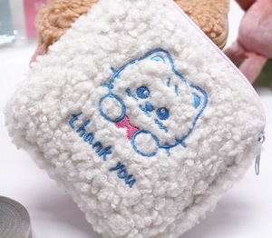 Close-up of white plush sanitary pad pouch with cute embroidered cat and thank you text