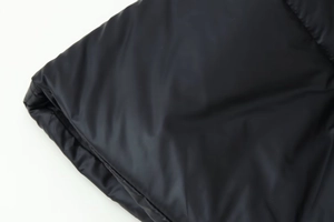 Close-up macro of black padded jacket fabric texture showing smooth nylon material surface