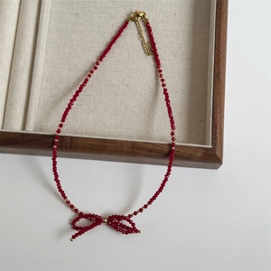 Detailed shot of handmade red faceted crystal bow necklace with golden beads