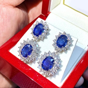 Dettaglio di orecchini pendenti ovali doppi con zirconi blu in una scatola rossa