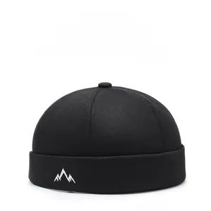 Detail of mountain peak embroidery on a black cotton brimless docker cap for outdoor wear
