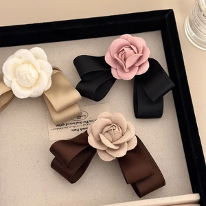 Elegant fabric camellia bow hair clips in multiple colors shown on a display tray
