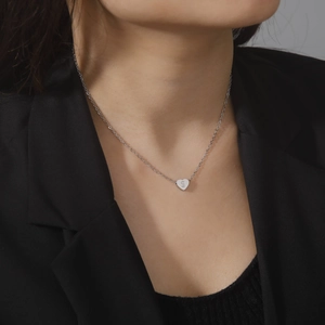 Polished stainless steel heart necklace with letter S engraving on a female model