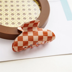 Macro view of brown and beige checkered claw clip on a minimalist woven tray