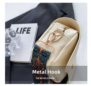 Close-up of creamy white lychee leather bag with golden hardware and floral strap