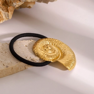 Close-up of golden shell-shaped metal charm on a black elastic hair tie for ponytails