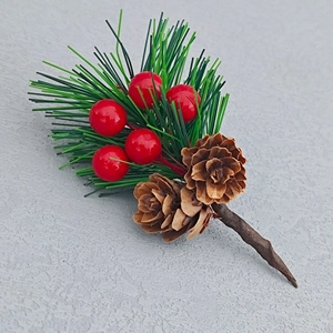 Detail of faux pine needles with red berries and natural pine cones for Christmas decor