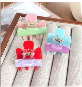 Close-up of bow-shaped acrylic hair claws in vibrant candy colors with gold metal springs