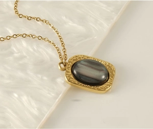 Detail of 18K gold stainless steel necklace with square pendant and oval natural stone