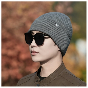 Close-up of grey ribbed knit beanie featuring FEHS metal tag and premium thick texture