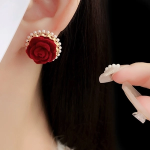 Gros plan de boucles d'oreilles roses en velours rouge avec perles et base dorée
