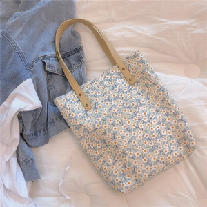 Sac cabas en toile fleurie avec anses en cuir et rivets vintage sur tissu blanc