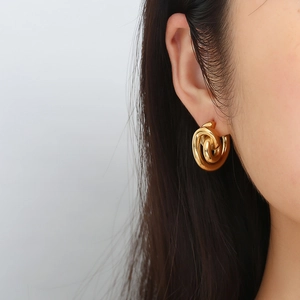 Boucles d'oreilles nœuds torsadés en acier inoxydable plaqué or 18K sur un mannequin