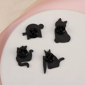 Macro shot of four black cat metal pins with butterfly clasps on a white ceramic plate