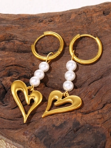 Macro detail of 18k gold heart earrings with white pearls on a textured wood background