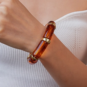 Detail view of amber resin tube beads and golden metal spacers on elastic bracelet