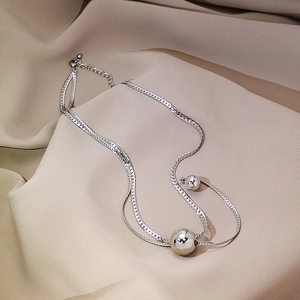 Detail of silver layered snake chain necklace with polished metal ball pendants