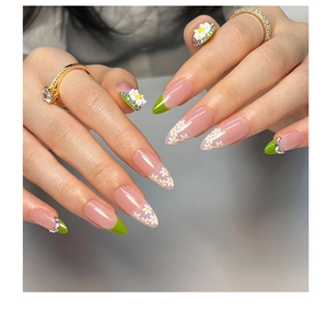 Detailed view of almond nails with green French tips, 3D white flowers and tiny rhinestones