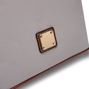 Detailed close-up of grey lychee textured leather and polished gold metal plaque