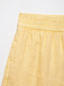 Detail of yellow pure linen shorts showing elastic waistband and natural fiber texture