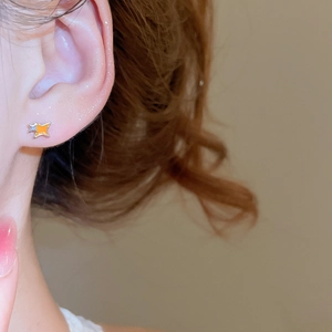 Gros plan de boucles d'oreilles en forme d'étoile avec émail orange et accents argent