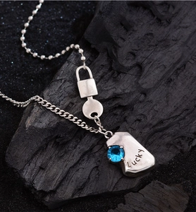 Macro shot of silver padlock and key pendant with blue zircon and Lucky engraving