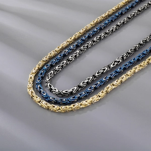 Detailed macro view of three Byzantine chains in gold, blue and black stainless steel