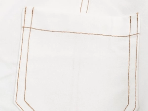 Detailopname van een witte katoen-linnen zak met contrasterende bruine stiksels op de stof