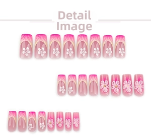 Detail of French 3D gradient blush press-on nails with white floral relief and golden beads