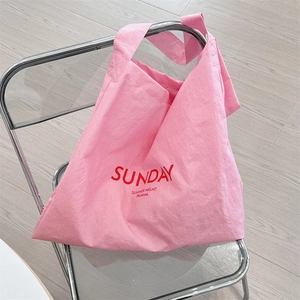 Detail of pink canvas tote bag featuring red Sunday print on a stylish modern chair