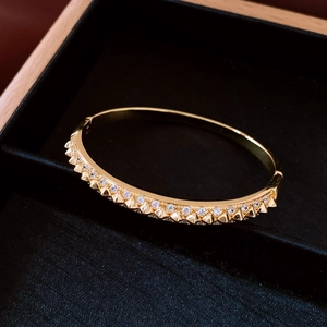 Macro shot of 18K gold plated rivet bangle with inlaid crystals in a black jewelry box