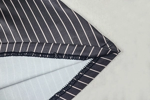 Macro detail of black and white striped fabric with precise double stitching on the hem