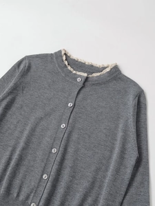 Close-up of grey knitted cardigan featuring beige lace trim collar and pearlized buttons