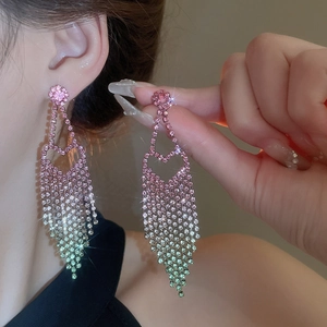 Detailed view of long heart tassel earrings with pink to green gradient rhinestones