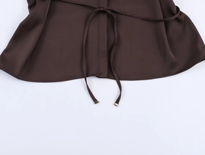 Détail de la texture satinée marron foncé avec embout de ceinture en métal et coutures