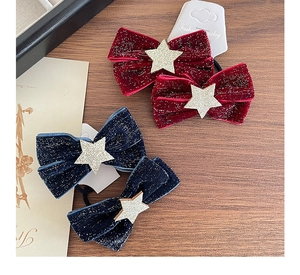 Detail of velvet star bow hair ties in burgundy and navy blue on a vintage wooden surface